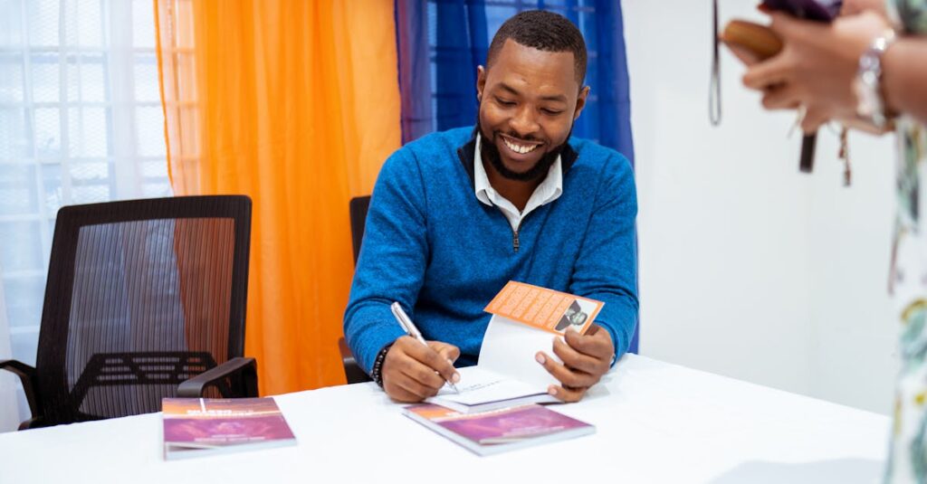 Smiling author signing books at a public event, engaging with readers.