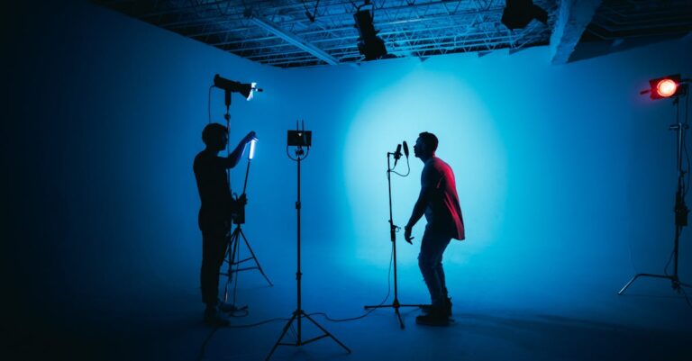 Silhouetted artists in a studio with dramatic lighting setup and microphone.
